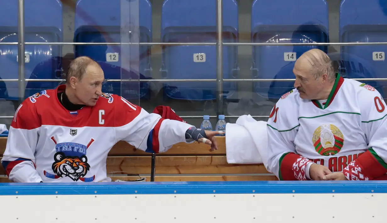 Presiden Rusia Vladimir Putin (kiri) dan Presiden Belarus Alexander Lukashenko (kanan) berbincang disela-sela pertandingan hoki es di Shayba Arena, Resor Laut Hitam Sochi, Rusia, (15/2). (Sergei Chirikov / Pool / AFP)