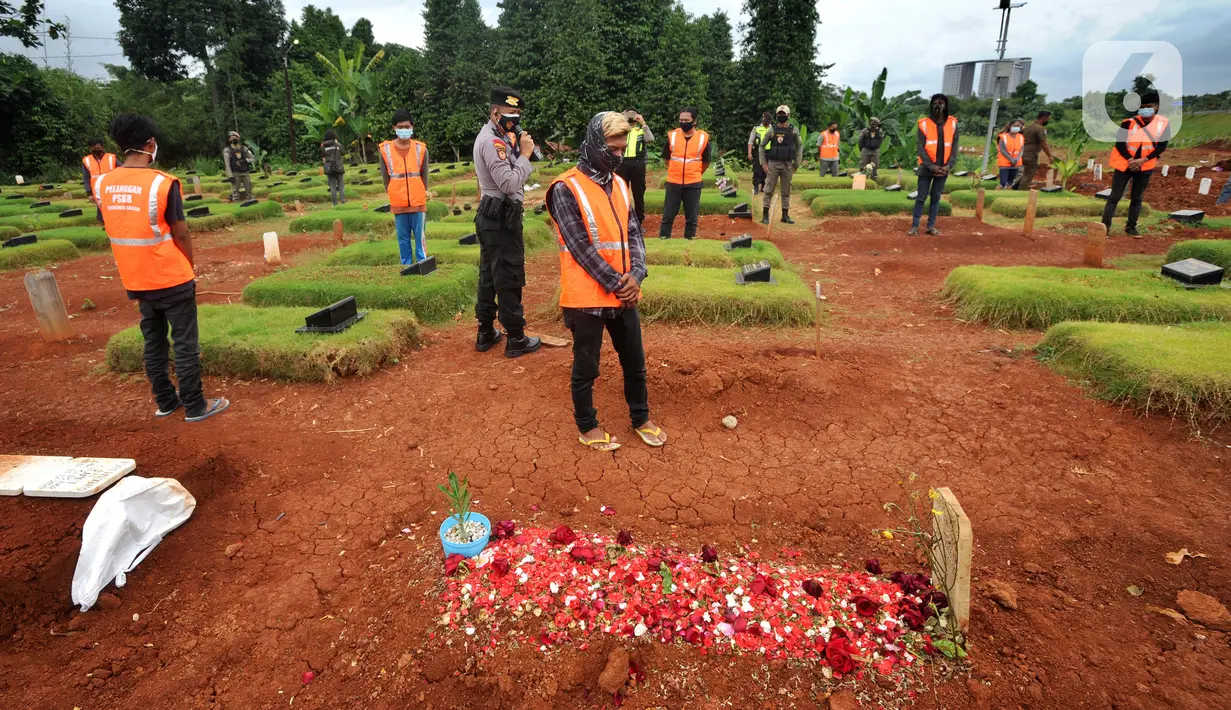 Sejumlah pelanggar PSBB berdoa di makam korban Covid-19 di TPU Jombang, Tangerang Selatan, Senin (18/1/2020). Petugas Satpol PP bersama Polres Tangsel memberikan hukuman bagi 17 pelanggar PSBB yang terkena razia masker di kawasan Bintaro. (merdeka.com/Arie Basuki)