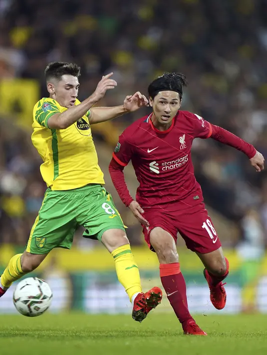 Gelandang Norwich City Billy Gilmour dan penyerang Liverpool Takumi Minamino berebut bola pada babak ketiga Piala Liga Inggris di Carrow Road, Rabu (22/9/2021) dinihari WIB. Liverpool sukses menghajar Norwich City tiga gol tanpa balas di kandang lawan. (Joe Giddens/PA via AP)