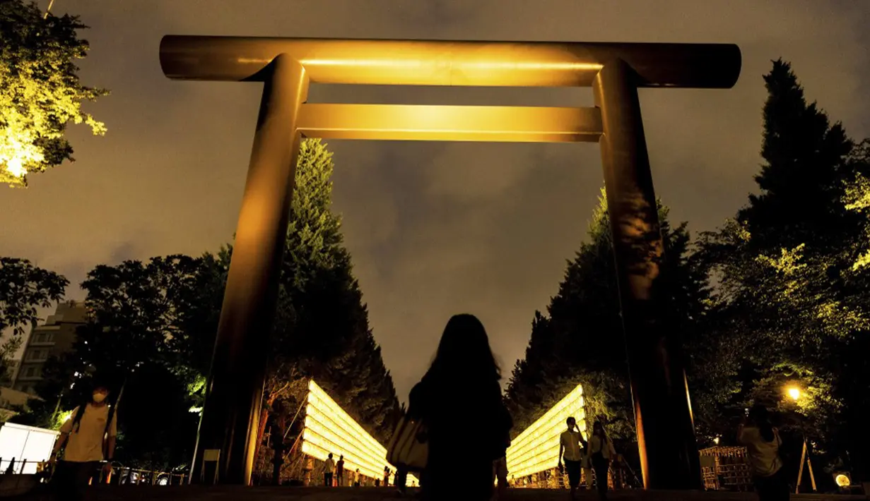 Pengunjung berjalan melewati lentera kertas saat Festival Mitama di Kuil Yasukuni, Tokyo, Jepang, Rabu (14/7/2021). Festival Mitama dirayakan sejak 1947 untuk menghormati jiwa para arwah yang diabadikan serta tentara yang gugur dari perang Jepang di masa lalu. (BEHROUZ MEHRI/AFP)