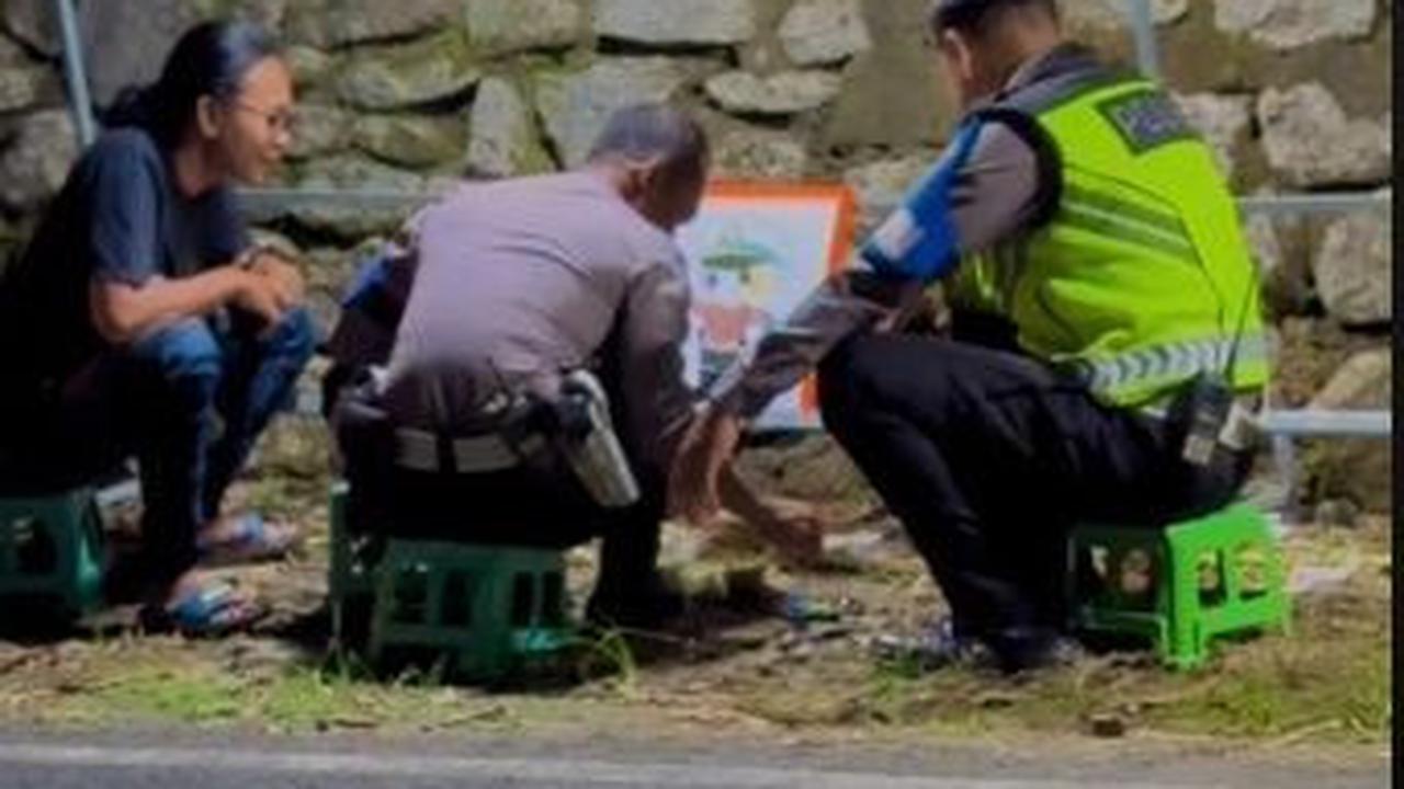 Lucunya, alih-alih berjaga, dua anggota polisi itu justru asik mewarnai gambar di pinggir jalan.