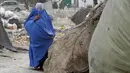 <p>Seorang perempuan yang mengenakan burqa berjalan di depan rumahnya di Kabul, Afghanistan, 8 Mei 2022. Taliban memerintahkan perempuan Afghanistan untuk mengenakan pakaian dari kepala hingga ujung kaki atau burqa tradisional di depan umum. (AP Photo/Ebrahim Noroozi)</p>