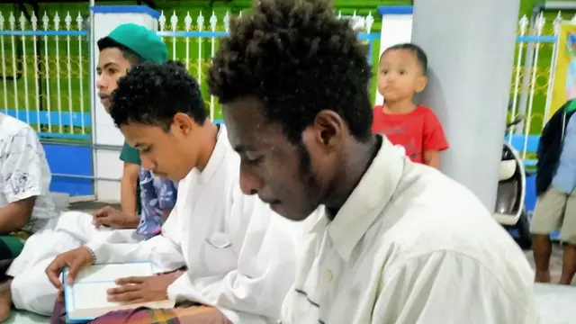 Mukhlis, Santri asal Papua tengah membaca Al Qur'an di sebuah Masjid Kota Kudus (Foto: Liputan6.com/Kusfitria Marstyasih)