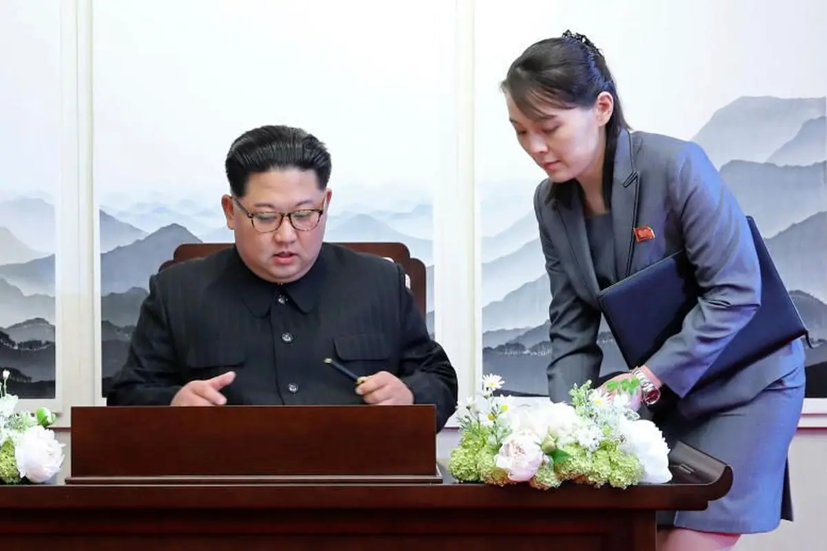 Kim Jong-un sedang menandatangani sebuah buku tamu dengan didampingi adiknya Kim Yo-jong.