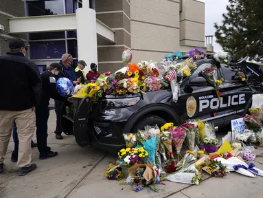 Warga meninggalkan karangan bunga di mobil polisi yang diparkir di luar Departemen Kepolisian Boulder setelah seorang petugas menjadi salah satu korban penembakan massal di toko King Soopers di Boulder, Colorado (23/3/2021). (AP Photo/David Zalubowski)