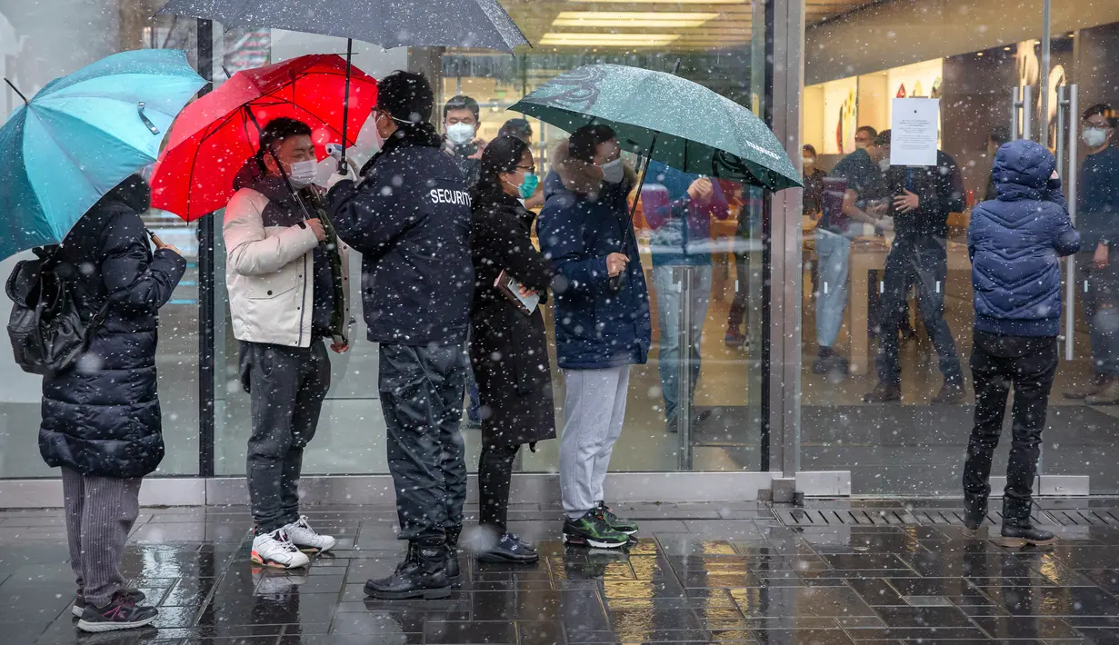 Petugas keamanan mengukur suhu tubuh pelanggan di luar Apple Store yang dibuka kembali di Beijing, China, Jumat (14/2/2020). Pembukaan kembali Apple Store ini dilakukan di tengah meningkat tajamnya korban tewas akibat virus corona di China. (AP Photo/Mark Schiefelbein)
