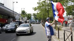 Seorang fans bernama Patrick, mengibarkan bendera Prancis saat menunggu keberangkatan tim ayam jantan dari hotel. (Bola.com/Vitalis Yogi Trisna)