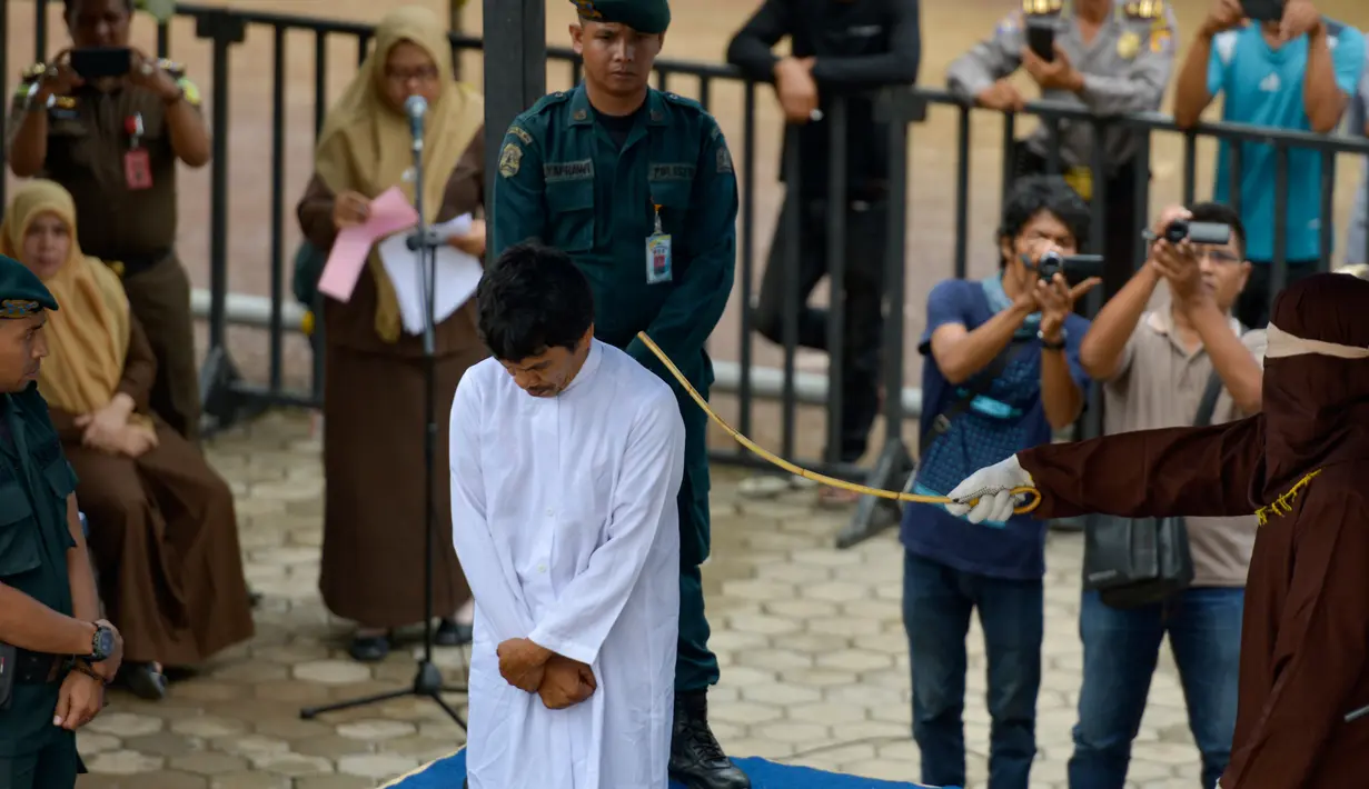 Terpidana pelanggaran syariat Islam menjalani hukum cambuk di Banda Aceh, Senin (21/10/2019). Mahkamah Syariah menvonis 6 kali sabetan cambuk setelah dipotong masa tahanan dua kali cambuk terhadap empat orang pria berprofesi sopir setelah tertangkap sedang bermain judi. (CHAIDEER MAHYUDDIN / AFP)