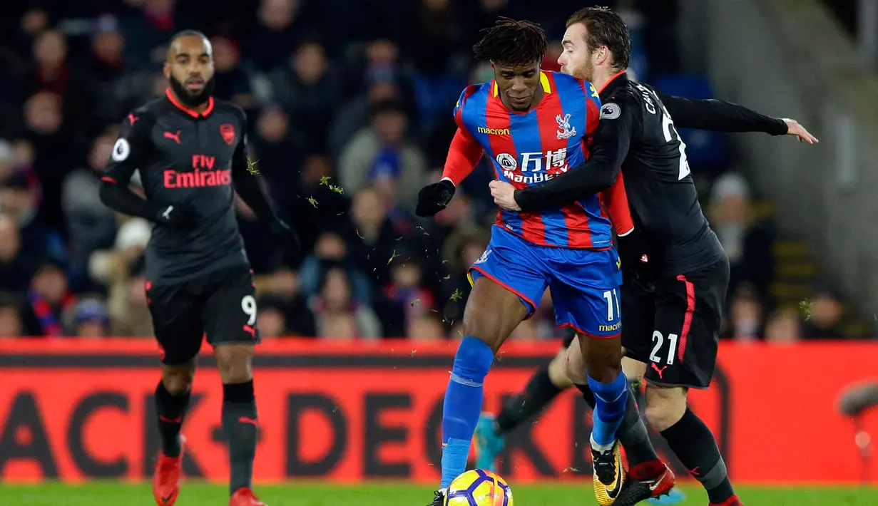 Pemain Arsenal, Calum Chambers berusaha menahan pemain Crystal Palace Wilfried Zaha saat pertandingan Liga Inggris di stadion Selhurst Park di London (28/12). (AP Photo/Alastair Grant)