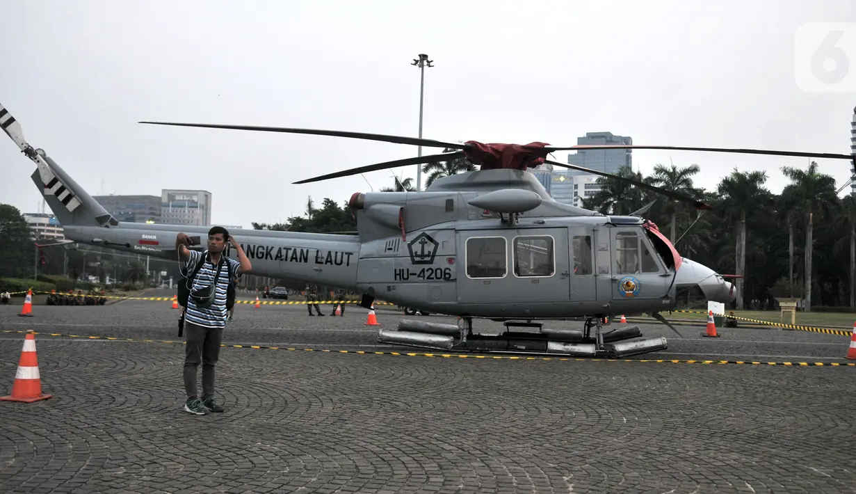 Warga berswafoto dengan helikopter TNI yang terparkir di kawasan Monas, Jakarta, Rabu (16/10/2019). Kehadiran empat helikopter TNI/Polri yang akan digunakan dalam apel pengamanan pelantikan presiden dan wakil presiden tersebut menarik perhatian pengunjung Monas. (merdeka.com/Iqbal Nugroho)