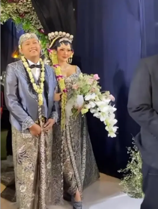 Sementara Denny Caknan mengenakan beskap abu yang dipadukan dengan kemeja putih, dasi pita dan kain batik. Tak ketinggalan blangkon sebagai pelengkap penampilannya.