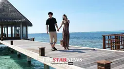 Dalam salah satu foto, Sungmin dan Kim Sa Eun tampak berpegangan tangan sambil berjalan-jalan menyaksikan pemandangan indah di pulau tersebut. (www.koreaboo.com)
