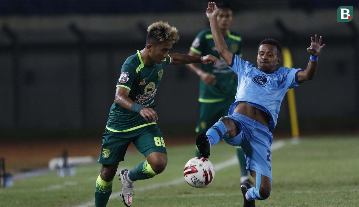 Striker Persebaya Surabaya, Muhammad Hambali Tolib (kiri) berusaha melewati hadangan striker Persela Lamongan, Prisca Elisa Womsiwor dalam laga Grup C Piala Menpora 2021 di Stadion Si Jalak Harupat, Bandung, Sabtu (3/4/2021). (Bola.com/Ikhwan Yanuar)