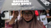 Seorang pekerja rumah tangga (PRT) menggunakan payung hitamsaat menggelar aksi di depan Taman Aspirasi Monas, Jakarta, Rabu (21/12/2022). Aksi tersebut dilakukan untuk memperingati Hari Ibu serta meminta pemerintah untuk mengesahkan Rancangan Undang-Undang Perlindungan Pekerja Rumah Tangga (RUU PPRT). (Liputan6.com/Faizal Fanani)