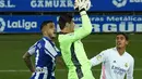 Kiper Belgia Real Madrid Thibaut Courtois melompat untuk melakukan penyelamatan selama pertandingan melawan Deportivo Alaves di stadion Mendizorroza di Vitoria. Minggu (24/1/2021). Alaves terpuruk di posisi ke-17 dengan nilai 18. Mereka hanya satu poin dari zona degradasi. (AFP/ Cesar Manso)