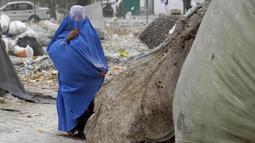 Seorang perempuan yang mengenakan burqa berjalan di depan rumahnya di Kabul, Afghanistan, 8 Mei 2022. Taliban memerintahkan perempuan Afghanistan untuk mengenakan pakaian dari kepala hingga ujung kaki atau burqa tradisional di depan umum. (AP Photo/Ebrahim Noroozi)