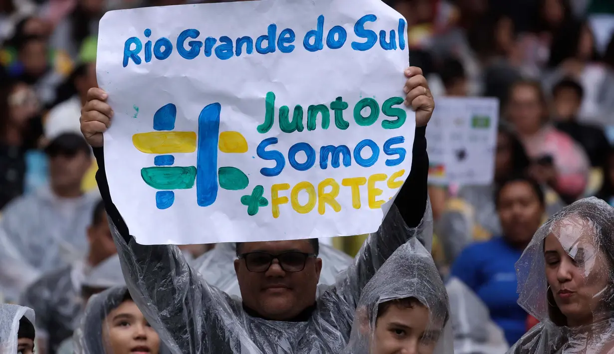Suporter mengangkat poster bertuliskan "Rio Grande do Sul Bersama Kita Lebih Kuat" saat menyaksikan pertandingan sepak bola di stadion Maracana, Rio de Janeiro, Minggu, 26 Mei 2024. (AP Photo/Bruna Prado)