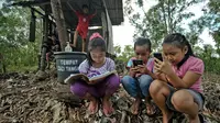 Siswa sekolah dasar mengikuti pembelajaran secara online menggunakan smartphone mereka di bukit Temulawak, Yogyakarta, Jumat (8/5/2020). Mereka harus ke atas bukit untuk mendapat sinyal yang bagus agar kegiatan belajar secara online dapat berlangsung. (AGUNG SUPRIYANTO/AFP)