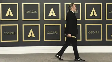 Aktor Joaquin Phoenix berjalan membawa piala Oscar 2020 usai berpose di ruang pers di  Dolby Teater, Los Angeles, Minggu (9/2/2020). Joaquin Phoenix yang memerankan karakter Arthur Fleck dalam film Joker, meraih penghargaan Oscar 2020 untuk kategori aktor terbaik. (AP Photo/Jordan Strauss)