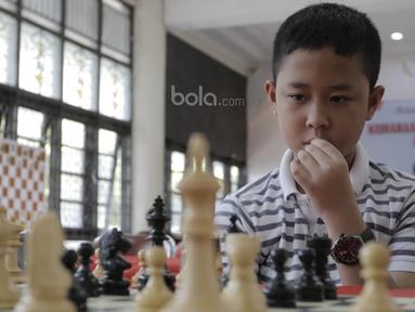 Seorang pecatur cilik tampak serius saat mengikuti kejuaraan catur daerah tingkat provinsi DKI Jakarta di Wisma Catur KONI Jakarta, Minggu (9/7/2017). Kejuaraan ini diikuti oleh 140 anak. (Bola.com/M Iqbal Ichsan)