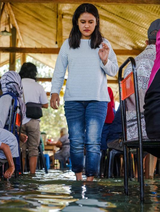 Seorang pengunjung berjalan di restoran kolam ikan di desa Wedomartani di Yogyakarta (15/11/2019). Jenis ikan yang terdapat di kolam restoran unik ini adalah ikan nila berukuran kecil-kecil. (AFP Photo/Oka Hamied)