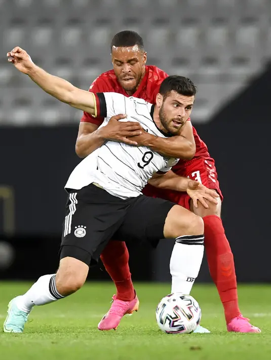Pemain Denmark Mathias Jorgensen (kiri) berebut bola dengan pemain Jerman Kevin Volland pada pertandingan persahabatan di Tivoli Stadion Tirol, Innsbruck, Austria, Rabu (2/6/2021). Pertandingan berakhir dengan skor 1-1. (AP Photo/Andreas Schaad)