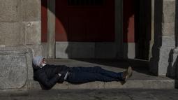 Seorang pria beristirahat di alun-alun Plaza Mayor di pusat kota Madrid, Kamis (10//2/2022). Warga Spanyol untuk pertama kalinya dalam hampir dua bulan diperbolehkan tidak menggunakan masker di luar ruangan setelah peraturan terkait hal itu dicabut pada Kamis. (AP Photo/Manu Fernandez)
