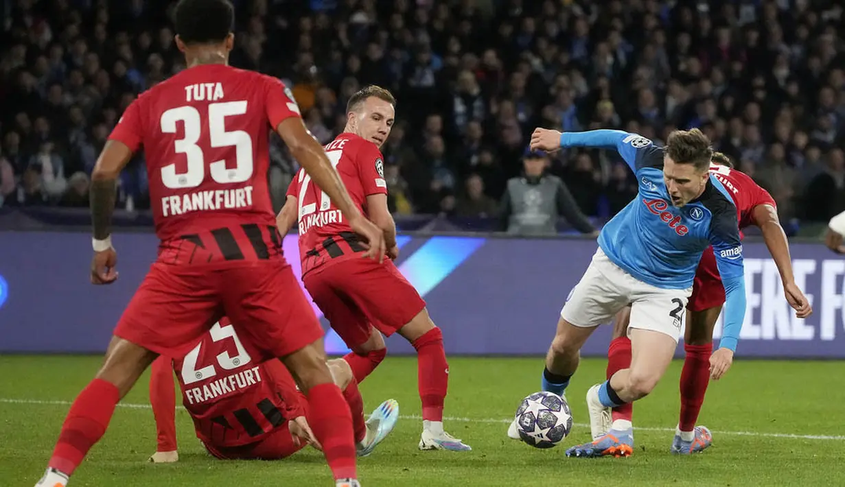 Pemain Napoli, Piotr Zielinski, berusaha melewati pemain Eintracht Frankfurt pada laga Liga Champions di Stadion Diego Armando Maradona, Kamis (16/3/2023). Napoli menang dengan skor 3-0. (AP Photo/Gregorio Borgia)