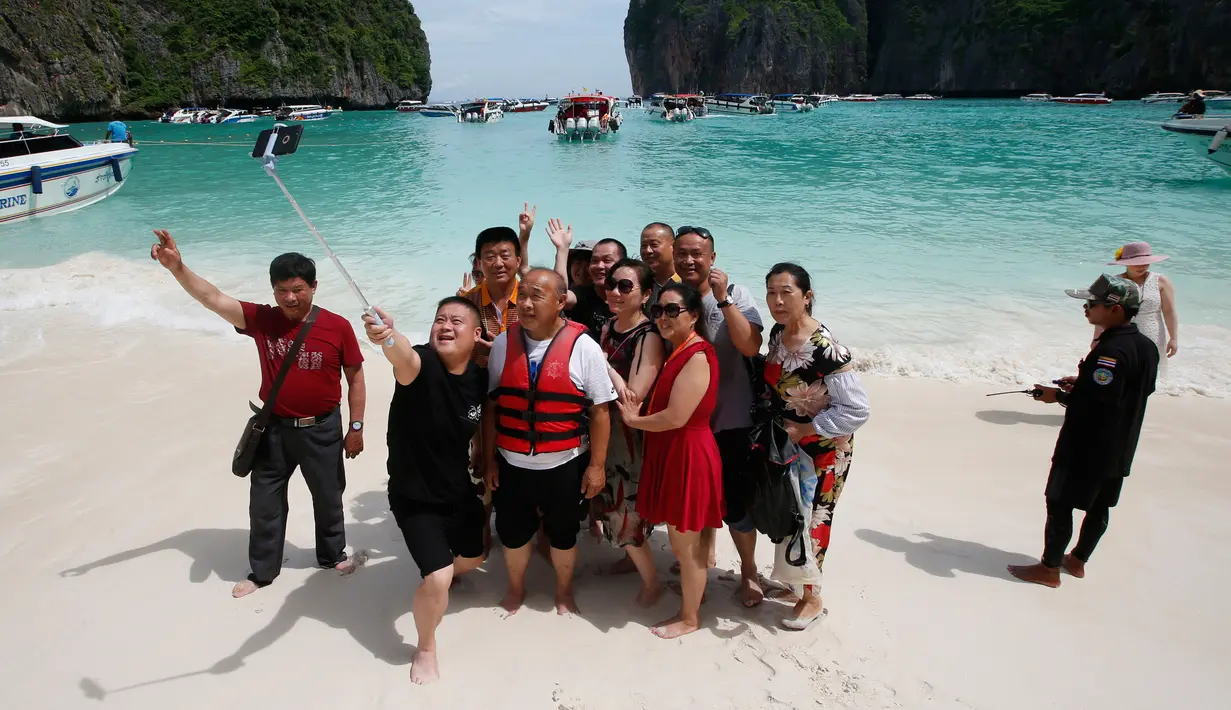 Wisawatan berswafoto dengan latar belakang pantai di Maya Bay, pulau Phi Phi Leh, Thailand, Kamis (31/5). Salah satu destinasi wisata tempat syuting film The Beach ini  akan ditutup selama empat bulan mulai 1 Juni 2018 mendatang. (AP Photo/Sakchai Lalit)