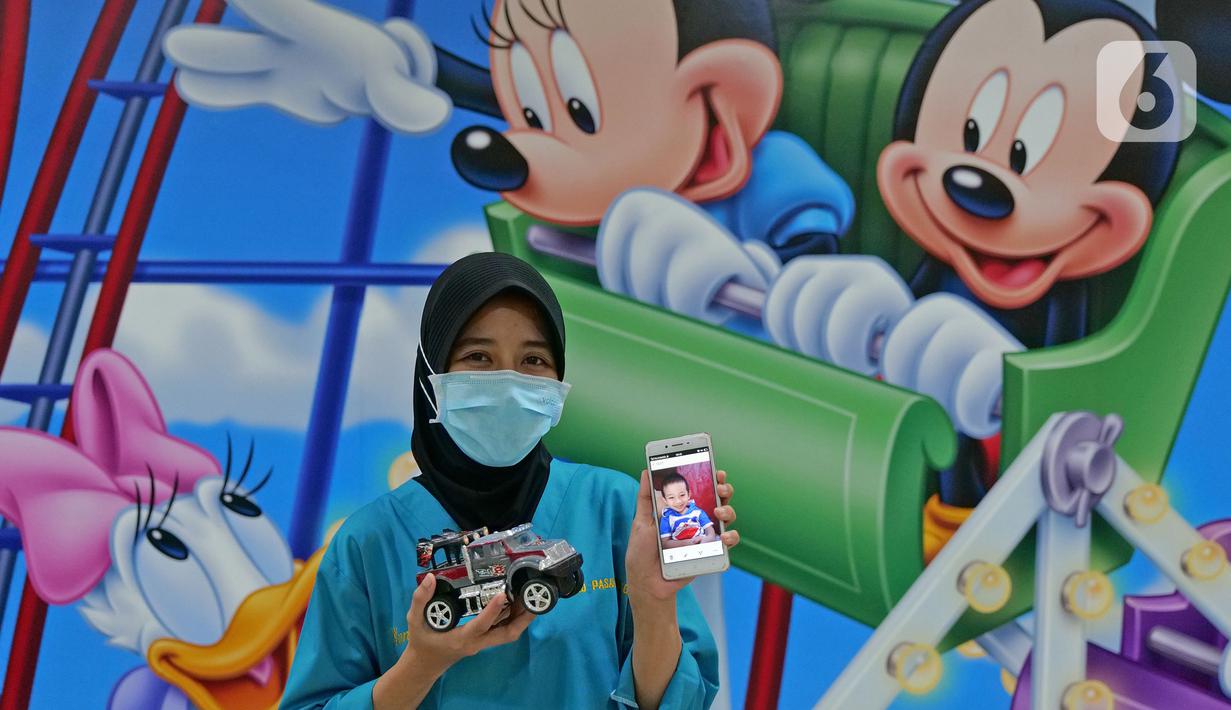 Perawat Yuni Rusmiyati (28) menunjukkan foto anaknya saat di RSUD Pasar Minggu, Jakarta, Jumat (22/5/2020). Yuni Rusmiyati sudah 2,5 bulan tidak bertemu keluarga selama bertugas menjaga COVID -19 di RSUD Pasar Minggu. (Liputan6.com/Herman Zakharia)