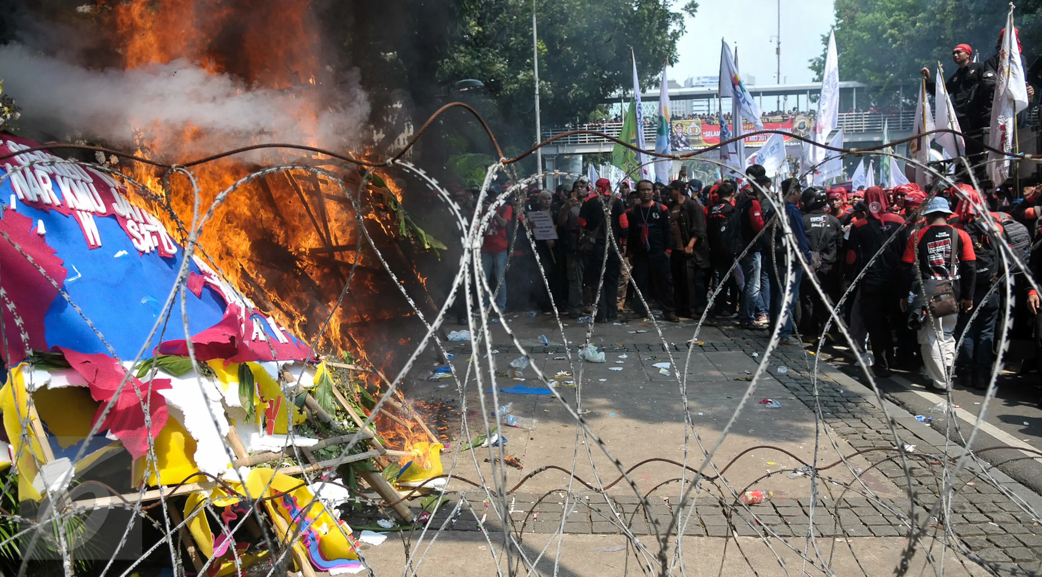 Karangan bunga untuk Ahok-Djarot dibakar oleh orang yang diduga menjadi provokasi saat aksi Hari Buruh di Jalan Medan Merdeka Barat, Jakarta, Senin (1/5). (Liputan6.com/Yoppy Renato)