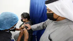 Seorang anak perempuan menerima dosis vaksin covid-19 Pfizer-BioNTech di pusat vaksinasi di Kuwait International Fairground di Kuwait City pada 3 Februari 2022. Kementerian kesehatan Kuwait mulai memvaksinasi anak usia 5 hingga 11 tahun. (YASSER AL-ZAYYAT / AFP)