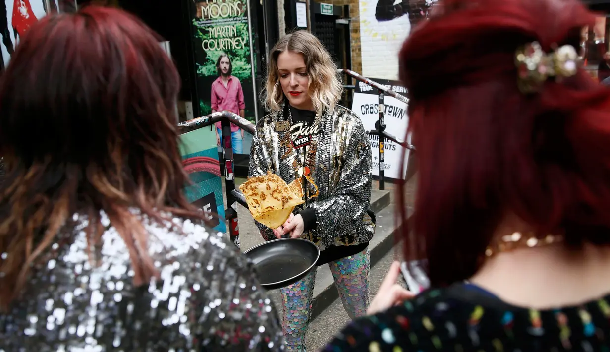 Seorang peserta berlatih membalik pancake dalam wajan sebelum mengikuti acara tahunan Great Spitalfields Pancake Race di London, Inggris, Selasa (9/2). Peserta diwajibkan berlari sambil membalik pancake tanpa membuatnya terjatuh. (REUTERS/Stefan Wermuth)