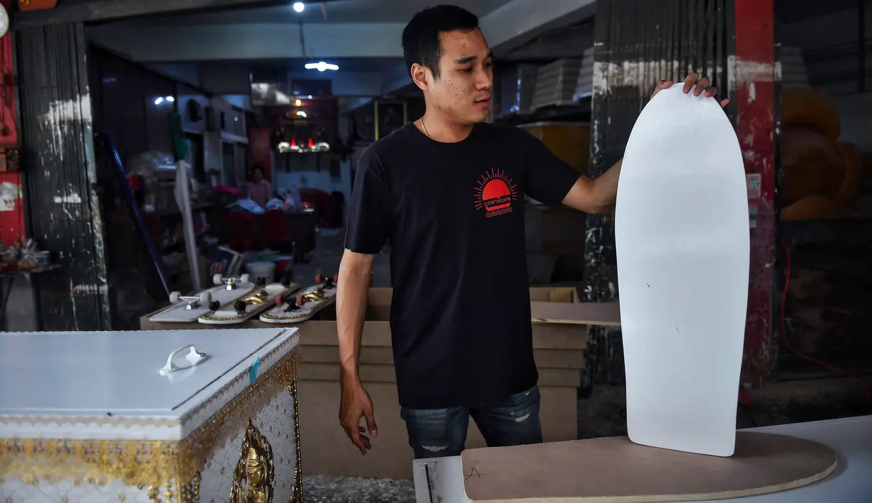 Pembuat peti mati Anusorn Yungyearn memajang skateboard dari kayu yang digunakan untuk peti mati, di toko peti mati Burapha di Bangkok, 19 Maret 2021. Pembuat peti mati di Thailand mengubah kayu peti mati sisa menjadi skateboard murah di tengah booming popularitas olahraga. (Lillian SUWANRUMPHA/AFP)