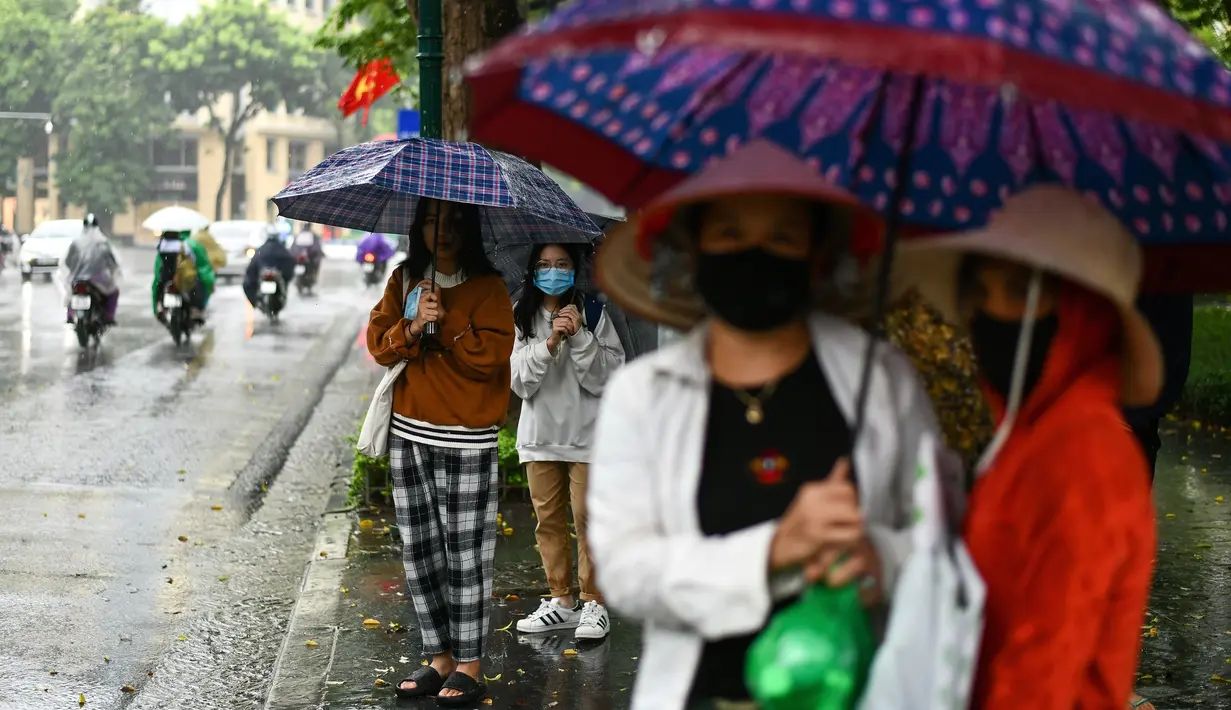 Para penumpang menunggu di halte bus selama hujan lebat di Hanoi (14/10/2020). Badai tropis Nangka menghantam Vietnam tengah-utara yang mengakibatkan bencana alam, terutama hujan lebat dan banjir, telah menyebabkan 28 orang tewas dan 12 lainnya hilang. (AFP Photo/Manan Vatsyayana)