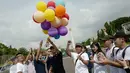 Massa yang tergabung dalam Generasi Muda Buddhis Indonesia (Gemabudhi) melepas balon sebagai tanda dimulainya gerakan membagikan bunga kepada pengguna jalan di depan Istana Negara, Jakarta, Sabtu (6/1). (Liputan6.com/Immanuel Antonius)