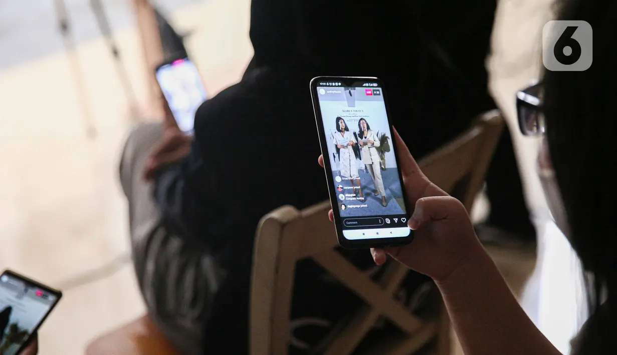 Penonton melihat ponsel yang menampilkan siaran langsung secara streaming peragaan busana rancangan Audrey Theola bertema Wonder Woman di Jakarta, Sabtu (24/10/2020). Fashion show virtual menjadi salah satu siasat pelaku industri mode ketika peragaan busana. (Liputan6.com/Faizal Fanani)