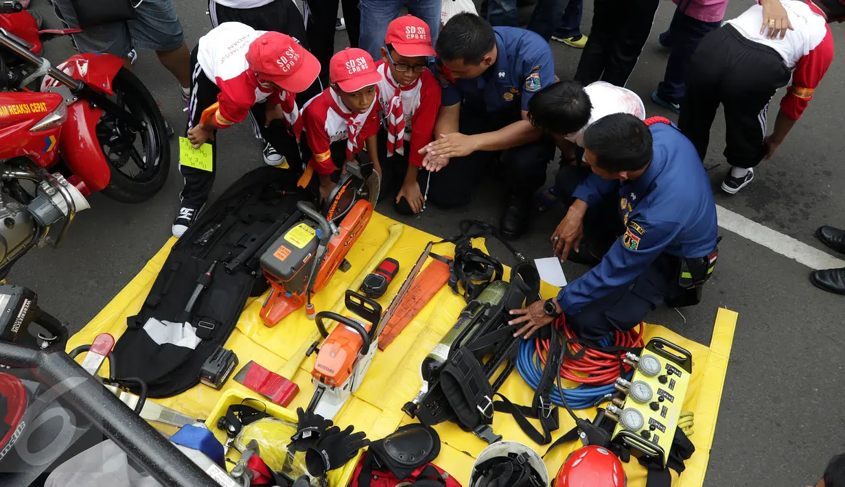Petugas memberitahu beragam alat dan fungsinya saat acara Madrasah Siaga Bencana di hari bebas kendaraan bermotor di kawasan Thamrin, Jakarta, Minggu (22/1). (Liputan6.com/Johan Tallo)