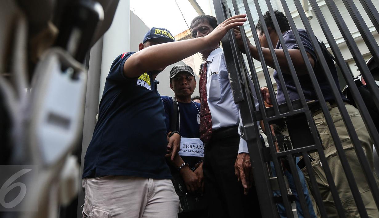 Seorang tersangka Ridwan Sitorus alias Ius Pane menjalani prarekonstruksi aksi perampokan dan pembunuhan di perumahan Pulomas, Jakarta Timur, Jumat (6/1). Sebanyak 71 adegan dilakukan untuk kelengkapan pemeriksaan. (Liputan6.com/Faizal Fanani)