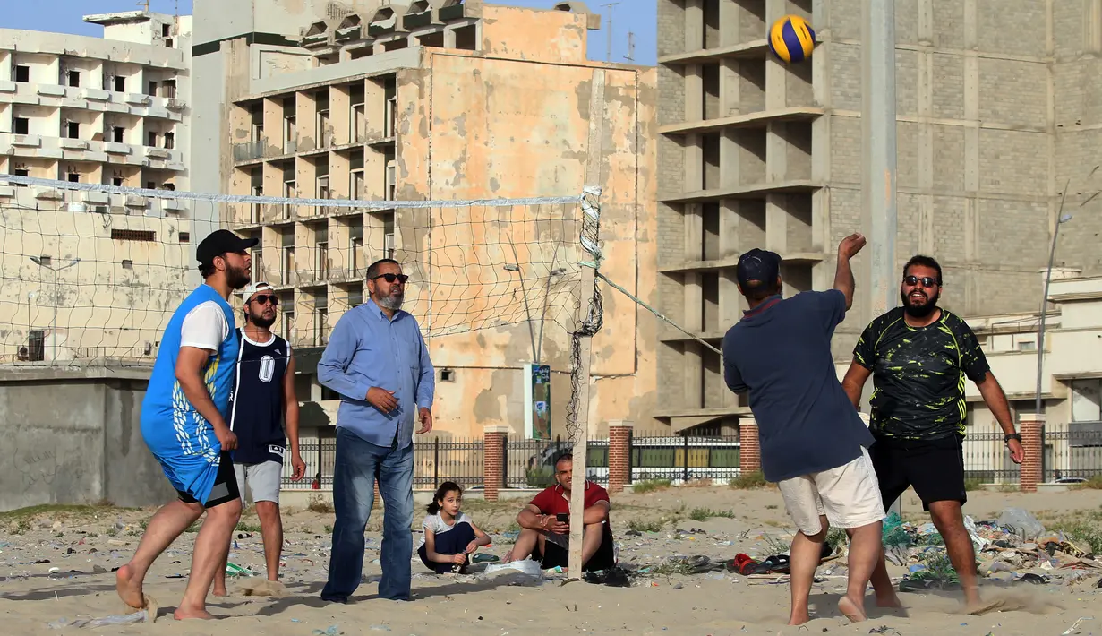 Orang-orang bermain voli pantai sembari menunggu waktu berbuka puasa selama bulan suci Ramadan, meskipun lockdown karena pandemi COVID-19, di ibu kota Tripoli, Libya pada Jumat (8/5/2020). (Photo by Mahmud TURKIA / AFP)