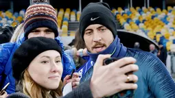 Penggemar wanita berselfie dengan gelandang Chelsea, Eden Hazard selama sesi pelatihan di NSC Olympiyskiy, Kiev, Ukraina (13/3). Pada leg pertama Chelsea menang telak atas Dynamo Kiev 3-0 di Stamford Bridge. (Reuters/Valentyn Ogirenko)