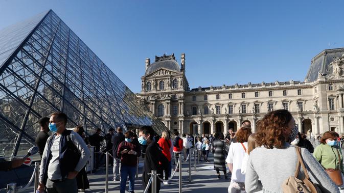 Pengunjung mengentre di piramida Louvre yang dirancang arsitek China Ieoh Ming Pei, pintu masuk ke Museum Louvre pada hari pertama pembukaan di Paris (6/7/2020). Setelah berbulan-bulan ditutup akibat lockdown Covid-19, Museum Louvre kembali dibuka pada 6 Juli 2020. (AFP/Francois Guillot)