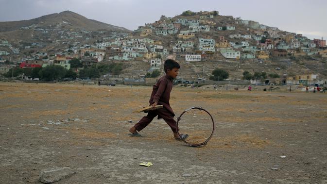 Seorang bocah Afghanistan mendorong roda saat terjadi badai pasir di pinggiran Kabul, Afghanistan (25/8/2020). Sebuah badai pasir hebat melanda Kabul. Badai menyebabkan jarak pandang jadi berkurang. (AP Photo / Rahmat Gul)