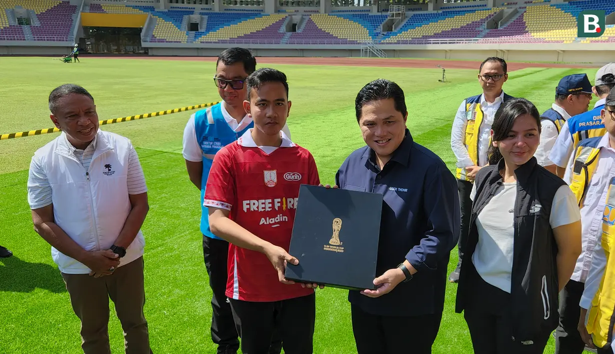 <p>Ketua Umum PSSI, Erick Thohir, menyerahkan souvenir Piala Dunia U-20 2023 kepada Wali Kota Solo, Gibran Rakabuming Raka, saat mengunjungi Stadion Manahan, Solo, Minggu (12/3/2023). (Bola.com/Radifa Arsa)</p>
