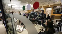 Polisi Carabinieri memeriksa kartu kesehatan Covid-19 pengunjung restoran pada hari pertama berlakunya ‘Super Green Pass’ di Roma, Senin (6/12/2021). Polisi Italia dapat memeriksa apakah pengunjung memiliki Green Pass yang menunjukkan bukti vaksinasi atau kesembuhan dari virus. (AP/Andrew Medichini)