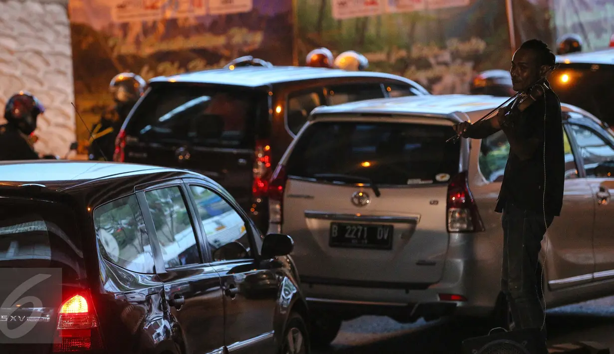 Oxill bermain biola menghibur pengendara yang terjebak macet di Jakarta, Rabu (6/1/2016). Dengan bermodal biola dan mini amplifier bertenaga aki motor, pria 32 tahun itu menghibur para pengendara yang melintas (Liputan6.com/Faizal Fanani)