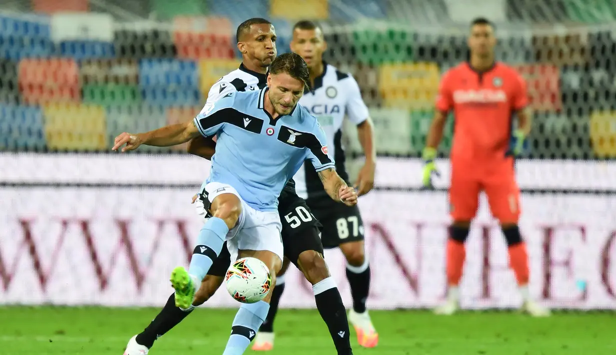 Penyerang Lazio, Ciro Immobile, berebut bola dengan bek Udinese, Rodrigo Becao, pada laga lanjutan Serie A pekan ke-33 di Dacia Arena, Kamis (16/7/2020) dini hari WIB. Lazio bermain imbang 0-0 atas Udinese. (AFP/Miguel Medina)