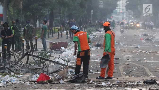 Petugas Penanganan Prasarana dan Sarana Umum (PPSU) atau Pasukan Oranye membersihkan sisa puing-puing pasca kerusuhan di kawasan Wahid Hasyim, Jakarta, Kamis (23/5/2019). Kerusuhan massa yang sebelumnya berdemo di depan gedung Bawaslu melebar ke Jalan Wahid Hasyim. (Liputan6.com/Herman Zakharia)