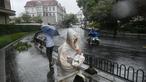 Pejalan kaki dan seorang pengendara sepeda motor menggunakan perlengkapan hujan saat cuaca buruk akibat Topan Bebinca di Shanghai pada Senin 16 September 2024. (Hector RETAMAL/AFP)