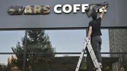 Seorang pekerja membuka sampul nama kedai kopi Stars Coffee yang baru dibuka di bekas lokasi gerai kopi Starbucks di Moskow, Rusia, Kamis (18/8/2022). Jaringan kedai kopi baru dibuka pada Kamis di Moskow, setelah penyanyi dan pengusaha Rusia Timur Yunusov, lebih dikenal sebagai Timati, bersama dengan pemilik restoran Rusia Anton Pinskiy membeli toko Starbucks setelah hengkangnya perusahaan asing dari negara itu. (AP Photo/Dmitry Serebryakov)